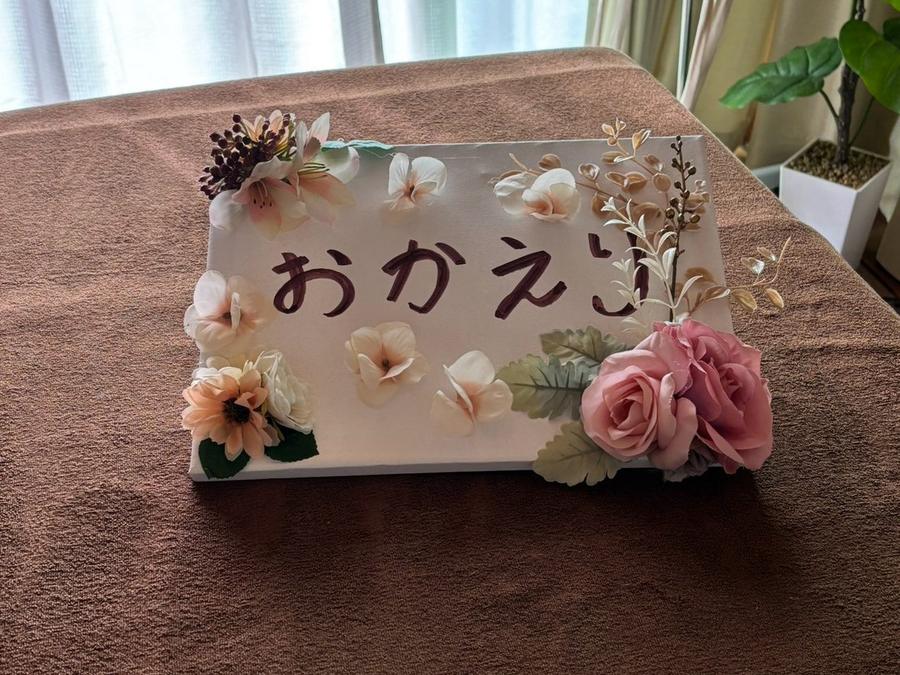 施術ベッドに置かれた「おかえり」のサインと花